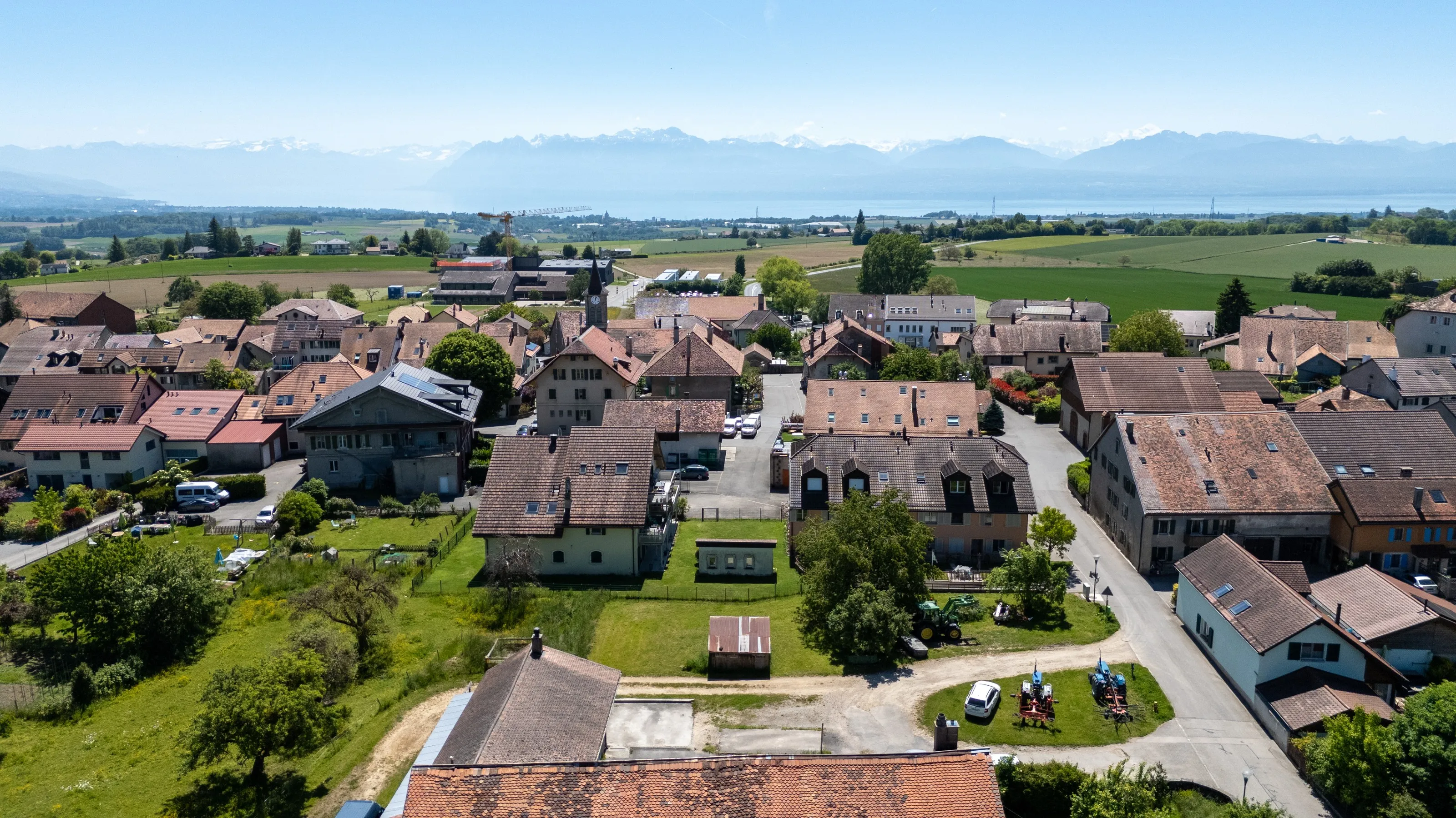 Le village d'Apples vu du ciel : toits de tuiles, champs, et le Léman au loin